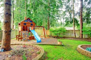 Photo of beautiful backyard with wooden children's play equipment and garden beds