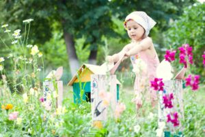 Photo of young girl in a garden with birdhouse and bunny sculptures made from logs