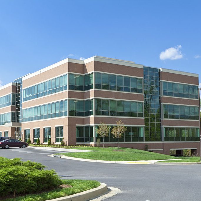 New office building in suburban Maryland, United States.  Parking lot in front of the building with several cars.